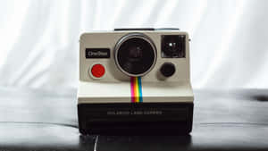 A Vintage Polaroid Camera On A Wooden Bookshelf Wallpaper