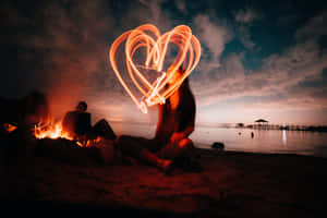 A Warm And Cozy Beach Bonfire Under The Starry Night Sky Wallpaper