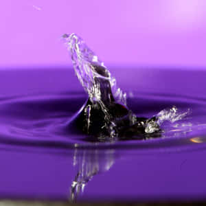 A Water Drop Is Falling Into A Purple Background Wallpaper