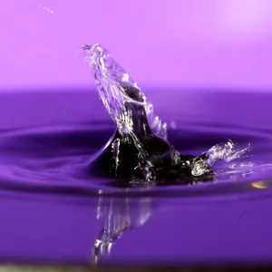 A Water Drop Is Falling Into A Purple Background Wallpaper