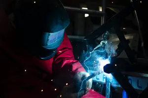 A Welder Is Welding Metal In A Dark Room Wallpaper