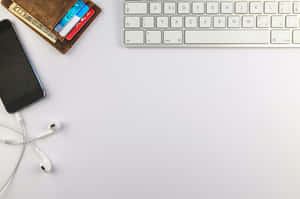 A White Desk With A Keyboard, Phone, And Headphones Wallpaper