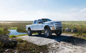 A White Truck Is Parked On A Dirt Road Near A Lake Wallpaper