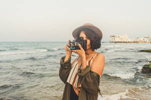 A Woman Capturing Her Special Moment On A Beach Wallpaper