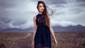 A Woman In A Blue Dress Standing In A Field Wallpaper