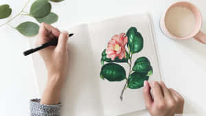 A Woman Is Drawing A Flower In A Notebook Wallpaper