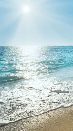 A Woman Is Sitting On A Beach With The Sun Shining On Her Wallpaper