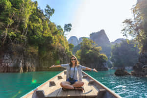 A Woman Is Sitting On A Boat In The Water Wallpaper