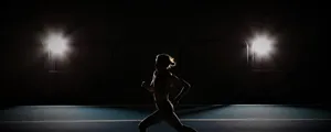 A Woman Running In The Dark On A Track Wallpaper