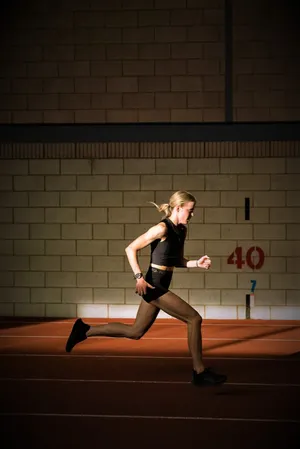 A Woman Running On A Track In A Dark Room Wallpaper