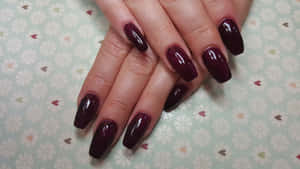 A Woman's Hand With Long Burgundy Nails Wallpaper