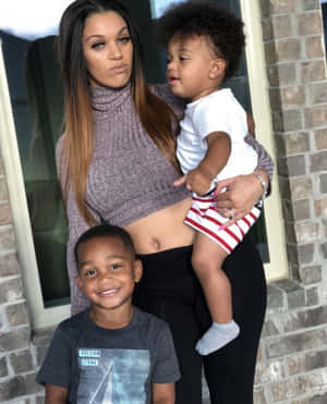 A Woman With Two Children Standing Next To A Brick Wall Wallpaper