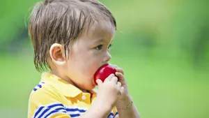 A Young Boy Eating An Apple Wallpaper
