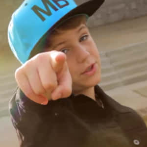 A Young Boy Pointing At Something With A Hat On Wallpaper