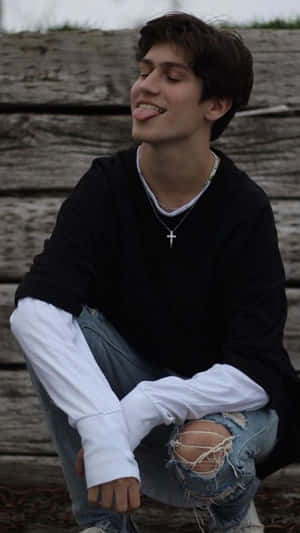 A Young Man Sitting On A Wooden Bench Wallpaper