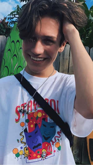 A Young Man Wearing A T - Shirt With A Cartoon Character On It Wallpaper