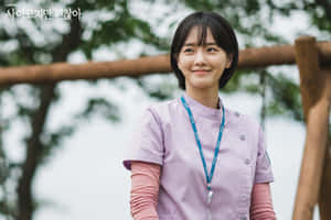 A Young Woman In A Purple Uniform Standing On A Wooden Bench Wallpaper