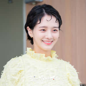 A Young Woman Smiling In A Yellow Dress Wallpaper