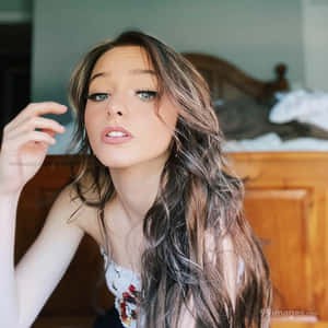 A Young Woman With Long Hair Posing On A Bed Wallpaper