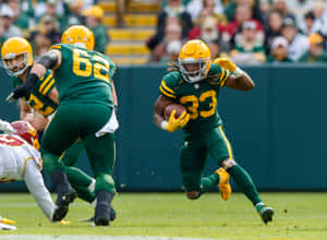 Aaron Jones Of The Green Bay Packers Running The Ball Down The Field. Wallpaper