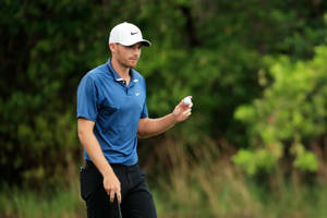 Aaron Wise Masterfully Holding A Golf Ball Wallpaper