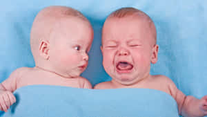 Adorable Twin Babies Displaying Discontent Wallpaper