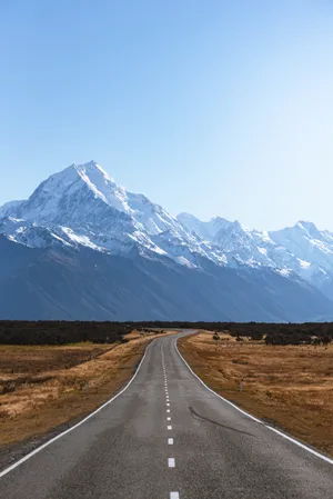 Adventure Is Out There: A View Of The Road Leading To A Mountain Wallpaper