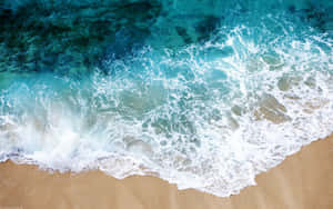 Aerial View Crystal Clear Waves Meeting Sandy Beach.jpg Wallpaper