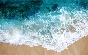 Aerial View Crystal Clear Waves Meeting Sandy Beach.jpg Wallpaper
