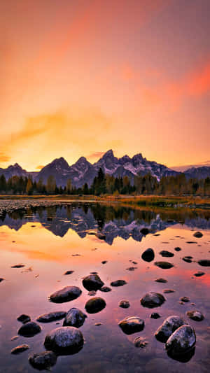 Aesthetic Sunset Iphone With Mountains And Forest Reflecting On Lake Wallpaper