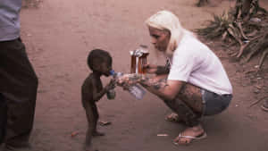 Aid Worker Quenching The Thirst Of An Emaciated Child Wallpaper