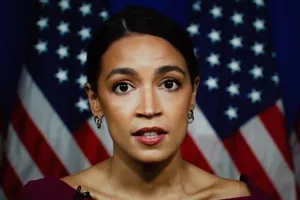 Alexandria Ocasio-cortez In Front Of American Flag Wallpaper