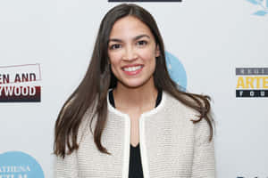 Alexandria Ocasio-cortez Smiling By White Backdrop Wallpaper