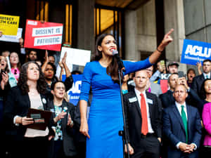Alexandria Ocasio-cortez Wearing A Blue Dress Wallpaper