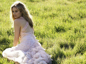 Alicia Silverstone Modeling On A Grassy Field Wallpaper