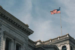 American Flag Waving Above Building Wallpaper