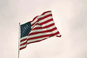 American Flag Waving Against Cloudy Sky Wallpaper