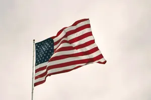 American Flag Waving Against Cloudy Sky Wallpaper