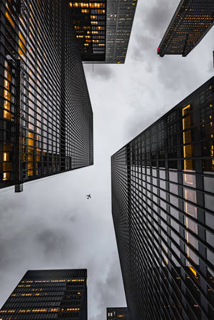 An Airplane Soaring Through The Sky Above The City Wallpaper