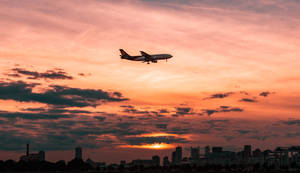 An Airplane Soars Above A Sprawling City Wallpaper