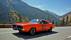 An Orange Muscle Car Driving Down A Mountain Road Wallpaper