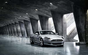 Aston Martin Db9 Cruising Through A Scenic Cityscape Wallpaper