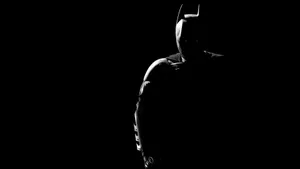 Batman In The Dark Silhouetted Against A Black Background Wallpaper