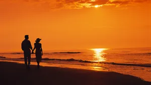 Beach Lovers Enjoying A Romantic Sunset Stroll Wallpaper