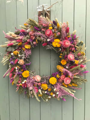 Beautiful Handcrafted Spring Wreath Adorning A Wooden Door Wallpaper