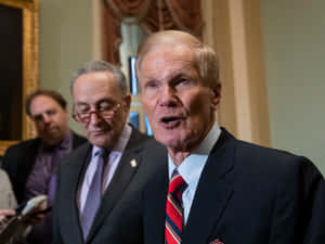 Bill Nelson In Black Suit And Red Tie Wallpaper