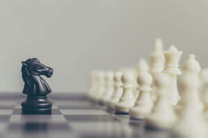 Black Knight Standing Against White Chess Pieces Wallpaper