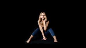 Blonde Woman Sitting Against Black Background Wallpaper