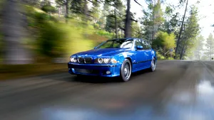 Blue_ Sedan_ Speeding_ Through_ Forest_ Road.jpg Wallpaper