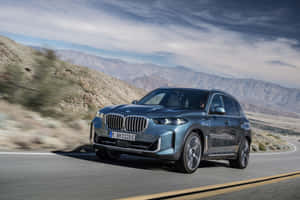 Bmw X5 On A Scenic Mountain Road Wallpaper